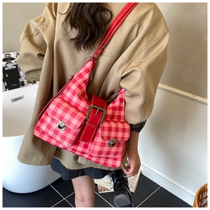 Detail of red plaid tote bag featuring front pockets with silver metal turn-lock closures