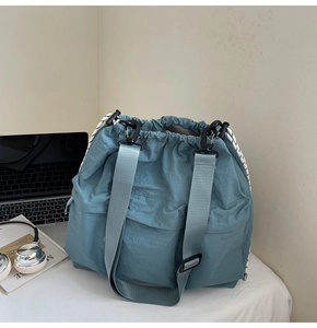 Close-up of blue nylon tote bag showing drawstring closure and spacious side pocket detail