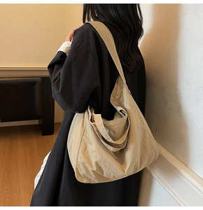 Gros plan d'un grand sac cabas beige en nylon avec large bandoulière sur un modèle