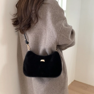 Détail du sac à bandoulière en fausse fourrure noire avec boucle dorée et crochets en métal