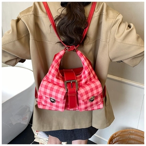 Detail of red and pink plaid tote bag with silver buckles and multi-pocket design