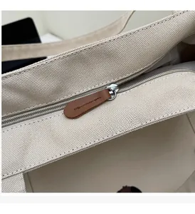 Detailed close-up of smooth metal zipper and brown leather pull on canvas tote bag