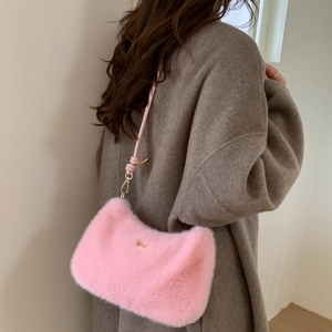 Détail du sac à main en peluche rose avec boucle dorée et bandoulière sur un manteau gris