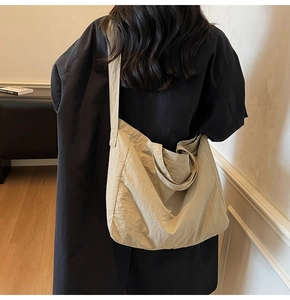 Detail of a large beige commuter tote bag showing pleated texture and spacious shoulder design