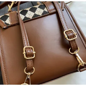 Detail of adjustable long shoulder strap and golden metal hook on brown PU backpack