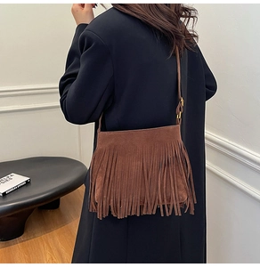 Detail der dunkelbraunen Wildleder-Beuteltasche mit Fransen an Model im Wollmantel