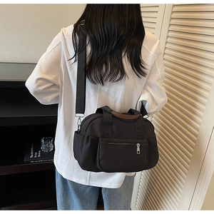 Detail of black canvas tote bag with brown handles and adjustable strap in lifestyle setting