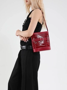 Sac seau rouge à motif crocodile avec boucle en métal porté par un mannequin de profil