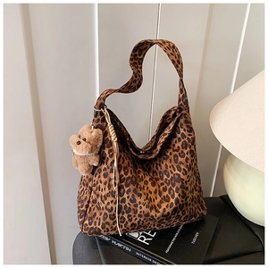 Detail of leopard print hobo tote bag featuring a cute brown plush bear charm and soft texture