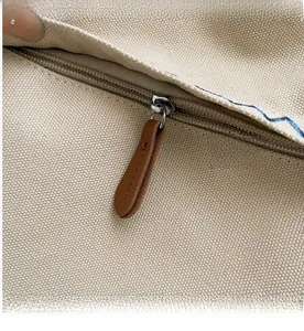 Close-up of smooth metal zipper and premium canvas texture on beige shoulder bag