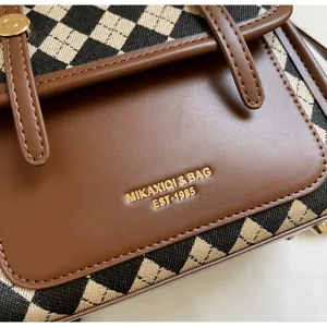 Close-up of vintage check fabric and brown leather bag with golden logo lettering