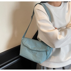 Close-up of light blue nylon crossbody bag featuring adjustable strap and wrinkled texture