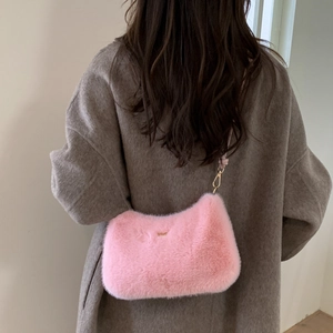 Détail du sac bandoulière rose en peluche avec boucle dorée sur un manteau en laine