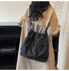 Detail view of black nylon drawstring crossbody bag with large cargo pockets on a model