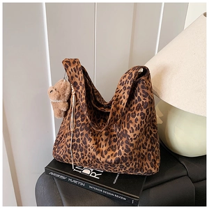 Close-up of leopard print tote bag with a brown plush bear charm in a stylish setting
