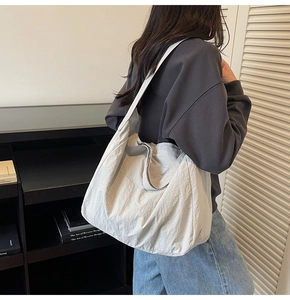 Grand sac cabas en nylon texturé blanc cassé porté à l'épaule dans une pièce épurée