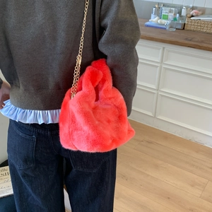 Detail of fluffy faux fur handbag in vibrant pink with golden chain strap on a model