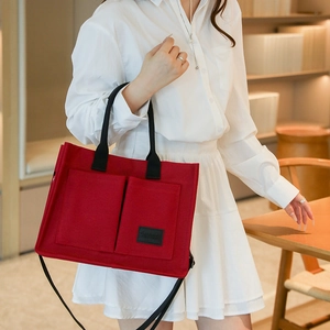 Détail d'un sac fourre-tout en toile rouge avec poches avant et larges bandoulières