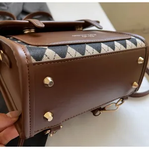 Detail view of reinforced brown leather bag bottom with four golden metal feet and stitching