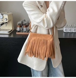 Detail einer braunen Wildledertasche mit langen Fransen, präsentiert an einem Model