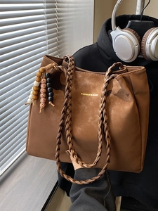Retro brown tote bag with woven handles and beaded tassels in a lifestyle setting