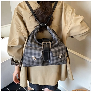 Detail of vintage checkered backpack featuring symmetrical flap pockets and silver buckles