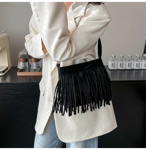 Detailansicht der schwarzen Wildleder-Fransentasche mit weißem Blazer im Retro-Look