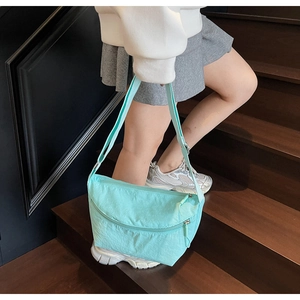 Detail of mint green nylon crossbody bag with pleated texture and adjustable strap