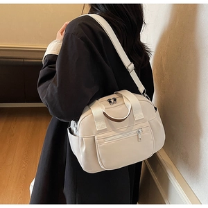 Model view of a large cream canvas tote bag with multiple zip pockets and shoulder strap
