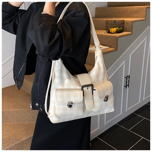 Detail of cream multi-pocket tote bag with subtle checkered texture and silver buckles