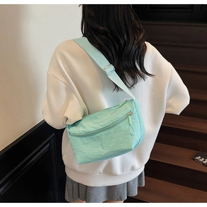 Detail of mint green nylon dumpling bag with pleated texture and adjustable strap