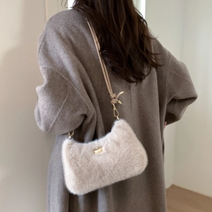 Détail du sac bandoulière en peluche abricot avec plaque dorée et bandoulière nouée