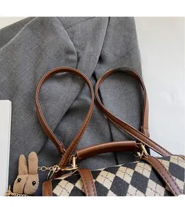 Close-up of diamond quilted tote bag with brown leather straps and bunny pendant charm