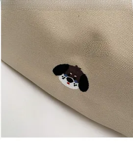 Detailed close-up of beige canvas texture with colorful cute dog head embroidery