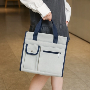 Detail of canvas tote bag with contrast handles and functional metal zipper pockets