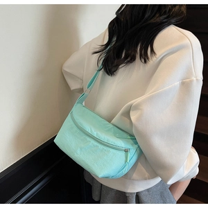 Detail of light mint green nylon crossbody bag showing crescent shape and wide strap