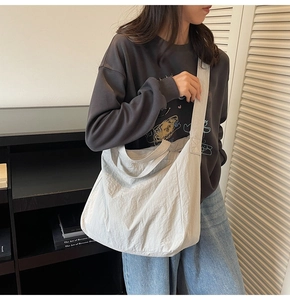 Détail d'un grand sac cabas beige en forme de lune avec texture en nylon plissé