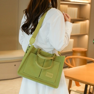 Détail du sac fourre-tout en toile vert clair avec bandoulière large et écusson de marque