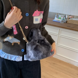 Detail of grey faux fur crossbody bag with golden chain strap on a model wearing a sweater