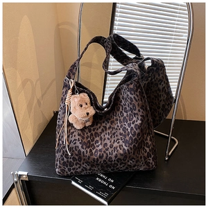 Detail of leopard print canvas tote bag with woven tassel and plush puppy pendant accessory