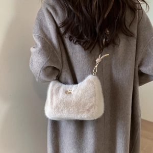 Gros plan du sac bandoulière en peluche crème avec détails dorés sur un manteau