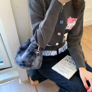 Detail of grey faux fur chain bag paired with a knit cardigan and blue denim jeans