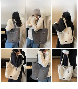 Detail of minimalist canvas tote bags in gray and cream white with dog embroidery