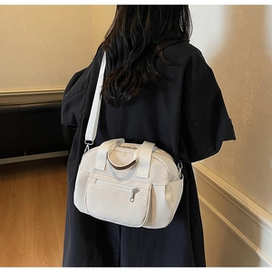 Detail view of cream canvas Boston bag with brown handles and wide fabric shoulder strap