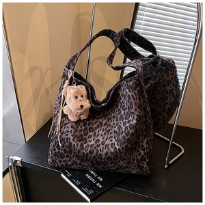 Detail of leopard print tote bag with brown plush dog charm and fringe tassels