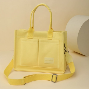 Détail du sac fourre-tout en toile jaune avec deux poches avant et bandoulière large amovible