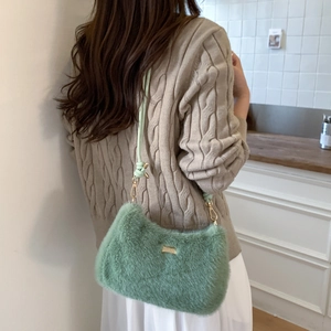 Détail du sac bandoulière en fausse fourrure vert clair avec plaque dorée et cordon