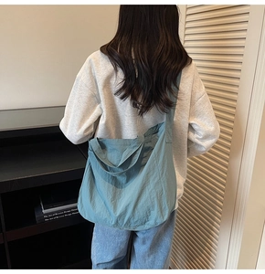 Détail du grand sac cabas bleu sarcelle avec texture nylon froissé porté par un modèle