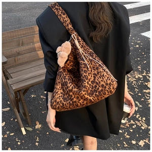 Outdoor street shot of large leopard print tote bag with plush bear and fringe details