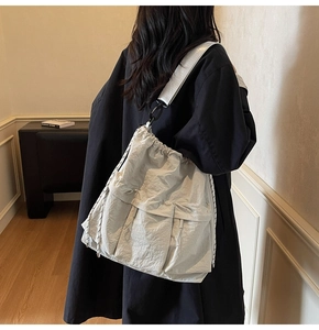 Detail of light gray nylon tote bag with drawstring closure and multiple utility pockets